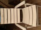 Twee houten witte tuinstoelen met kussens en tuinslang 