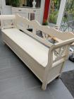 Lange witte houten bank met opbergruimte.